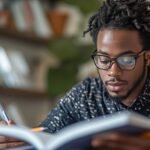 Revision Guide - male student reading from a opened book